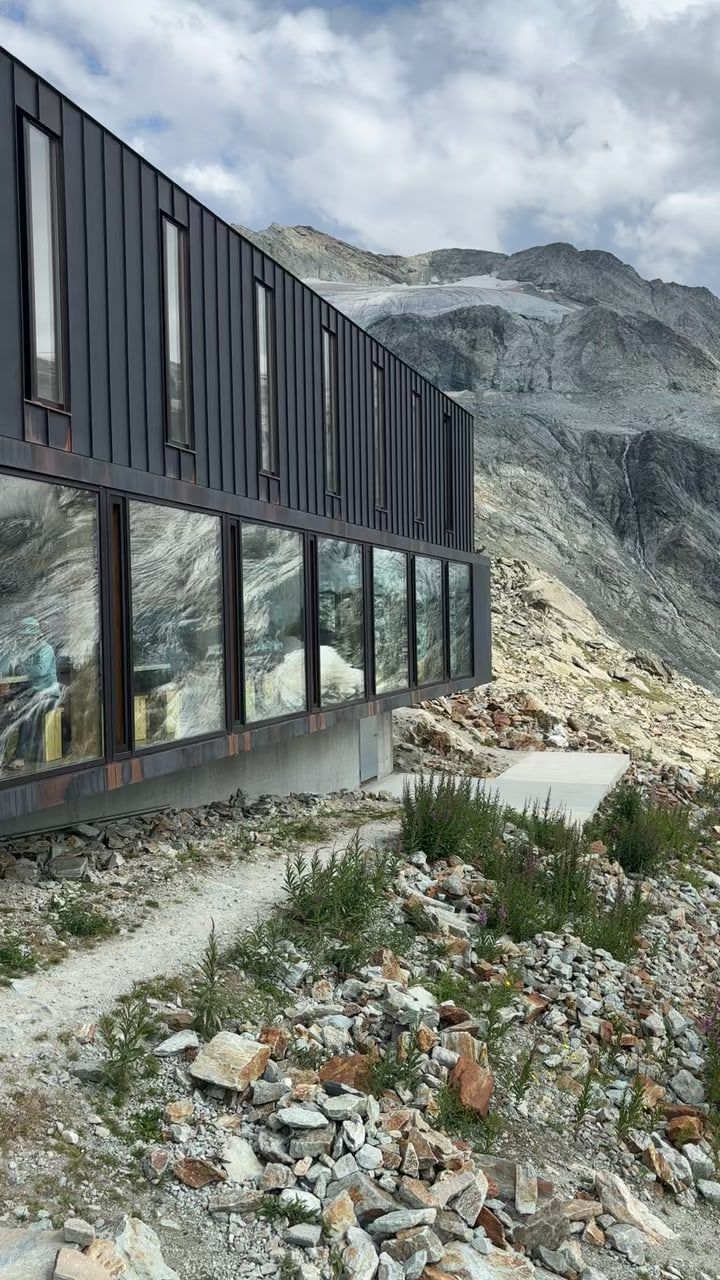 The Moiry hut, a modern dark metal building with large windows, set on the rocks facing the Moiry glacier