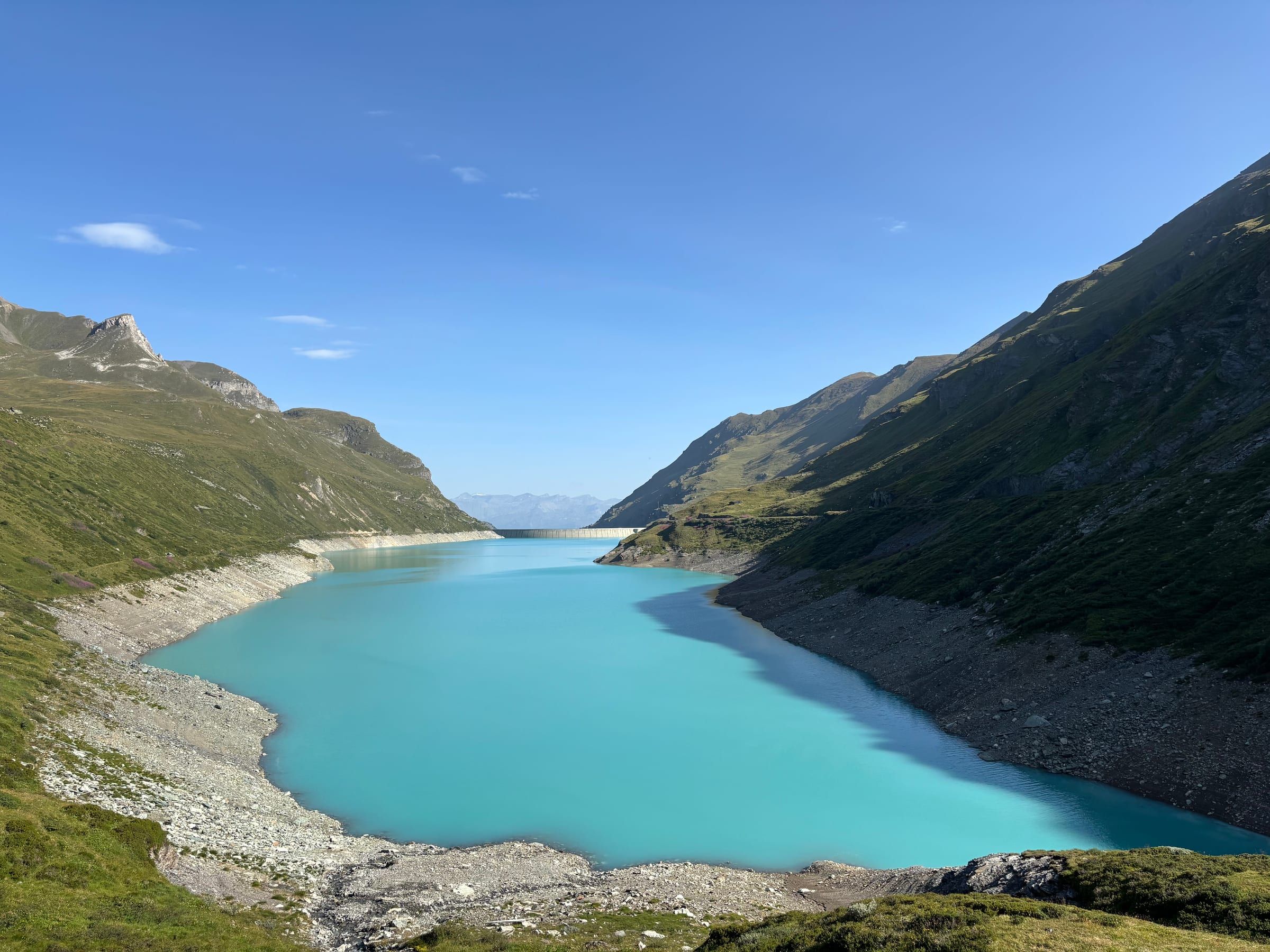The turquoise Lac de Moiry between green slopes, with the dam in the distance